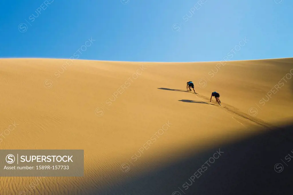 Hispanic couple climbing sand dune