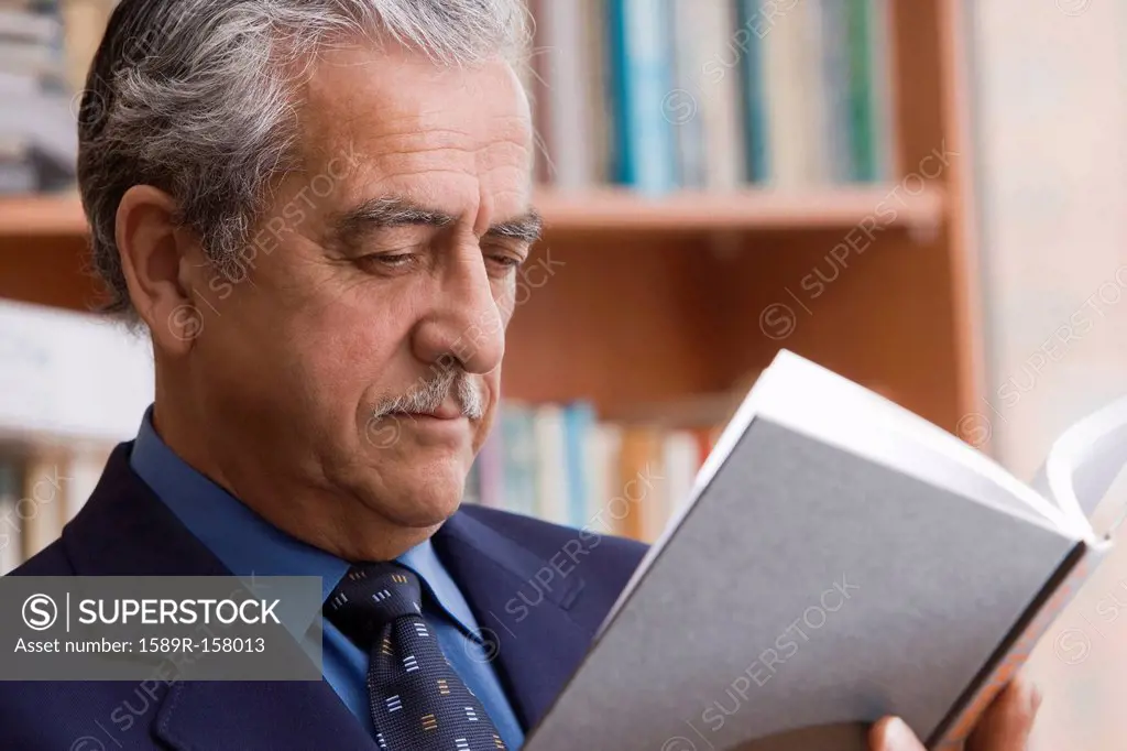 Hispanic businessman reading book