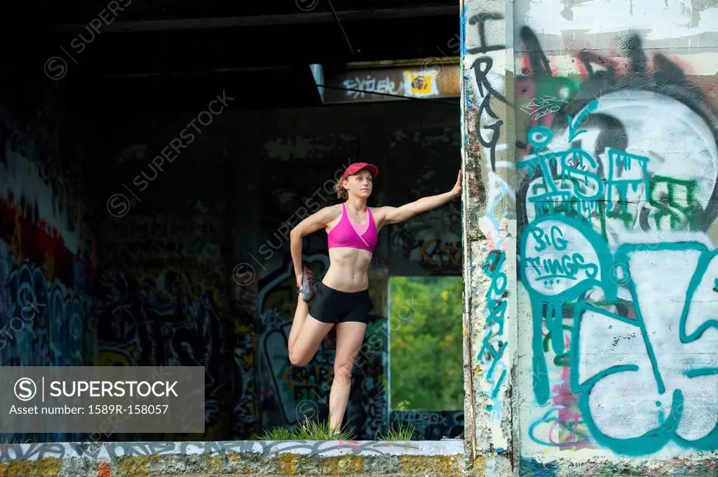 Caucasian woman stretching in abandoned loading dock