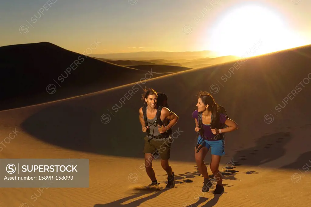 Hispanic couple walking up sand dune