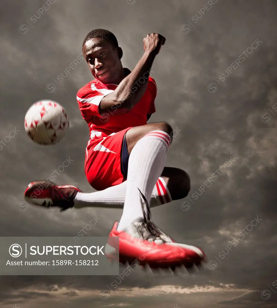 Black soccer player kicking ball