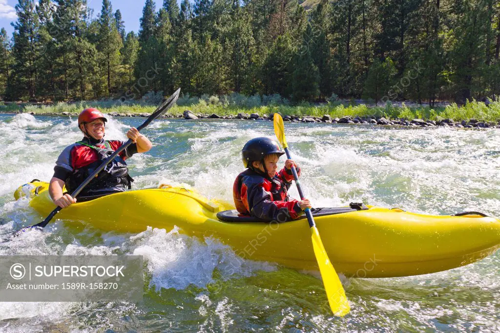 Caucasian father and son kayaking in river