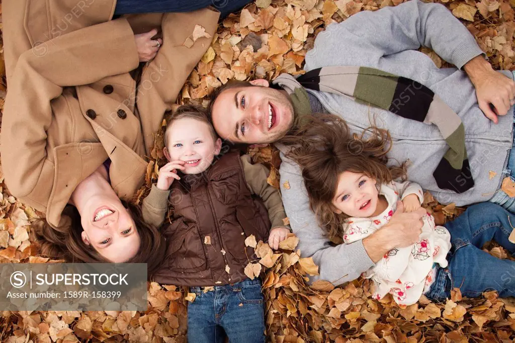 Caucasian family laying in autumn leaves