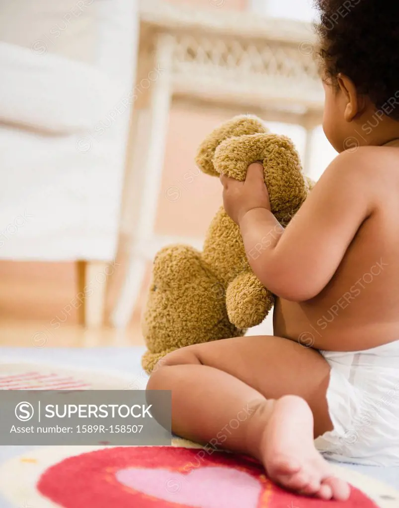Black baby girl holding teddy bear
