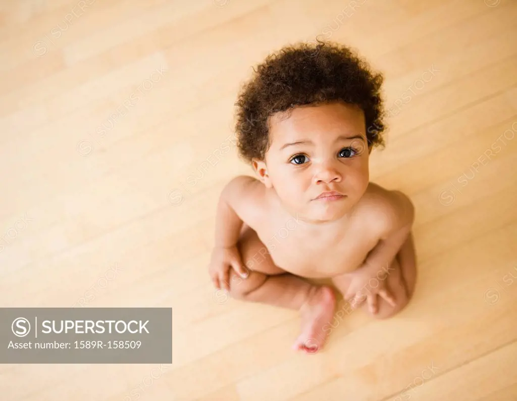 Serious Black baby girl sitting on floor