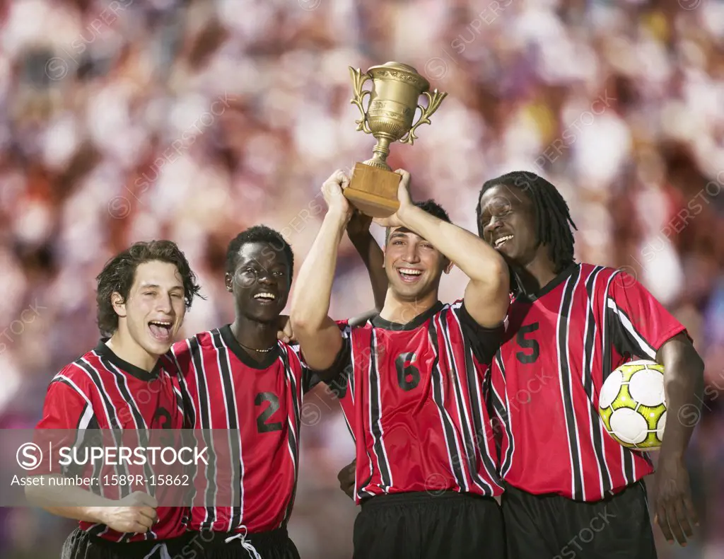 Soccer players triumphantly holding up trophy