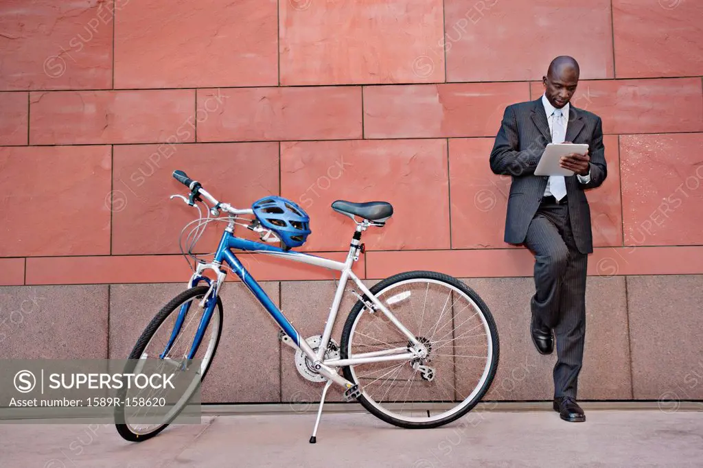 Businessman using digital tablet near bicycle