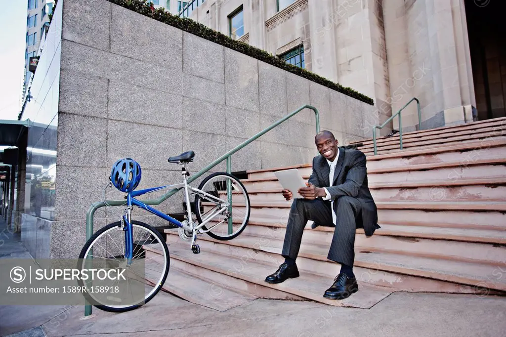Businessman sitting on stairs using digital tablet