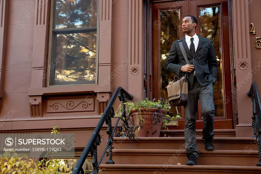 Black businessman walking down front stoop steps