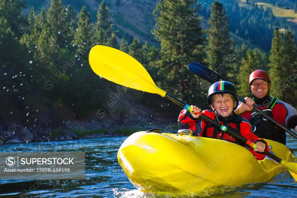 Caucasian father and son kayaking on river