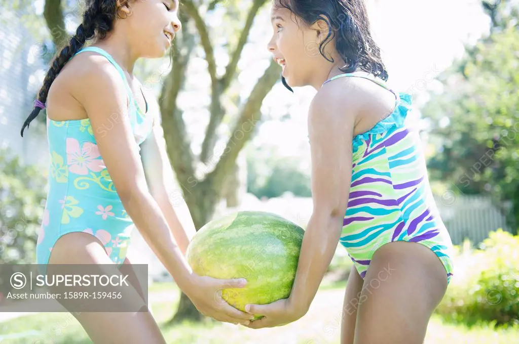 Hispanic girls carrying watermelon together