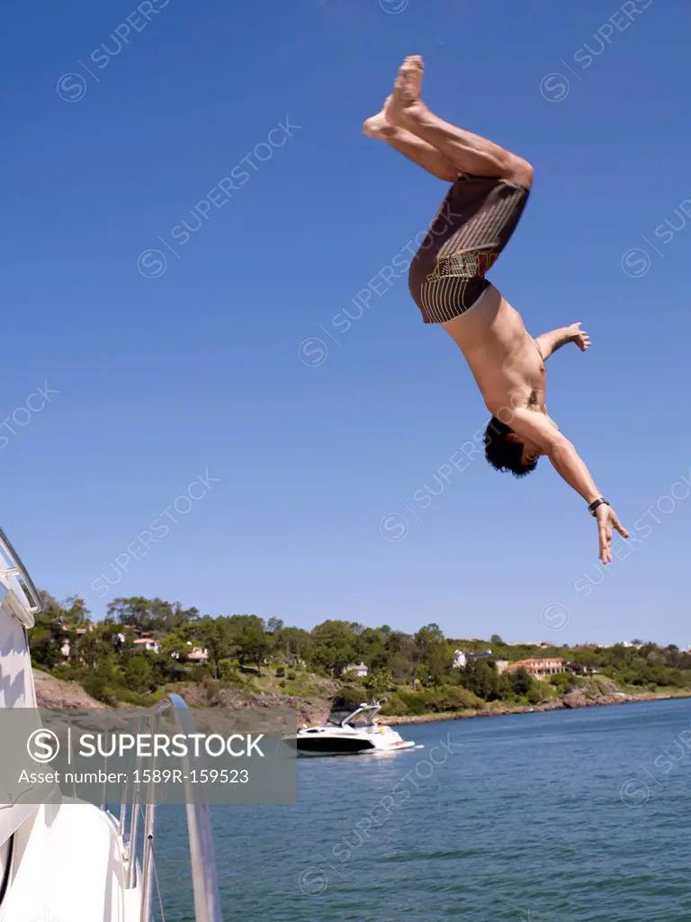 Hispanic man jumping from sailboat