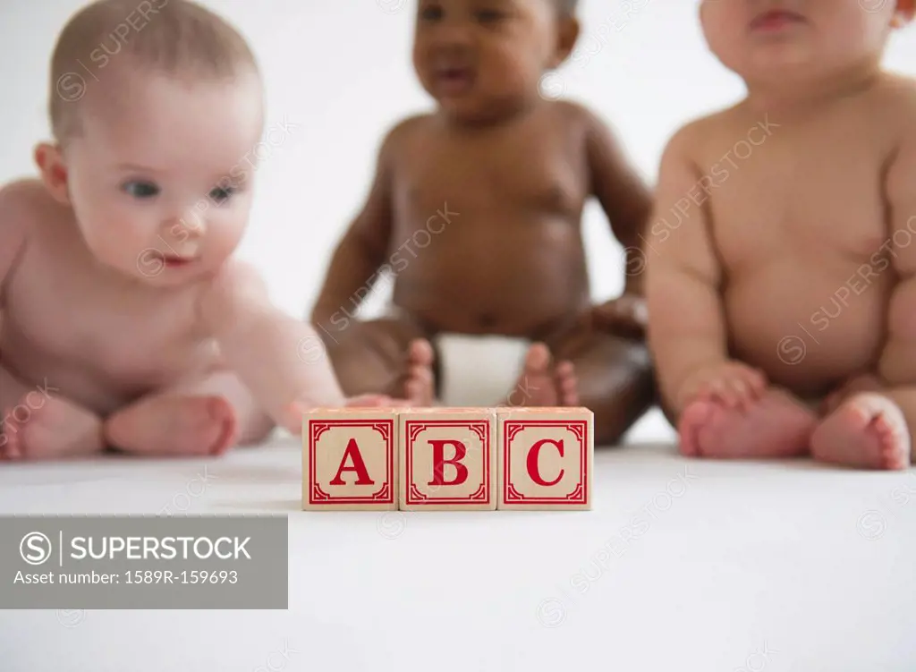Babies sitting with alphabet blocks