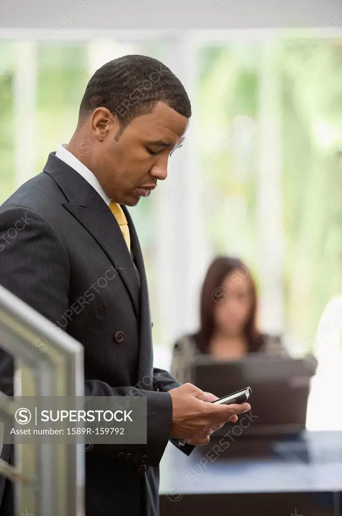 Mixed race businessman text messaging on cell phone