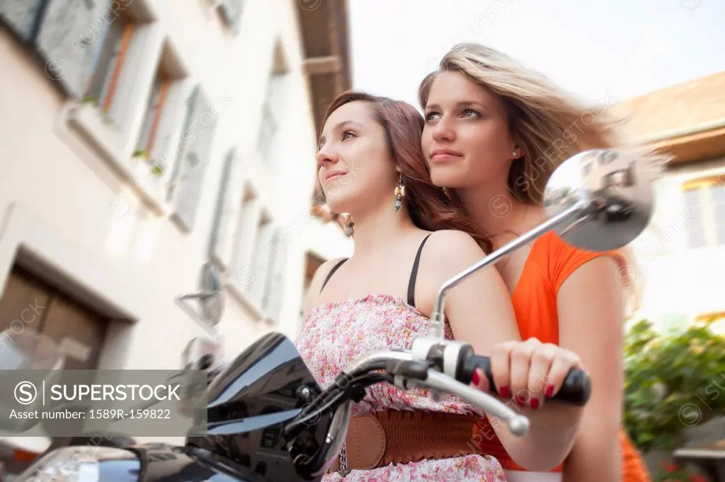 Caucasian friends riding scooter together