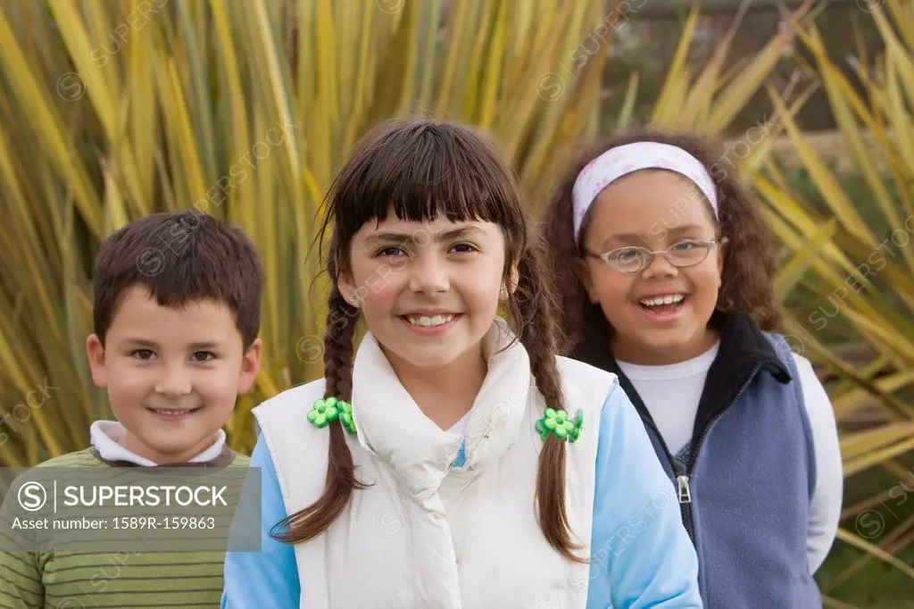 Smiling Hispanic children standing outdoors