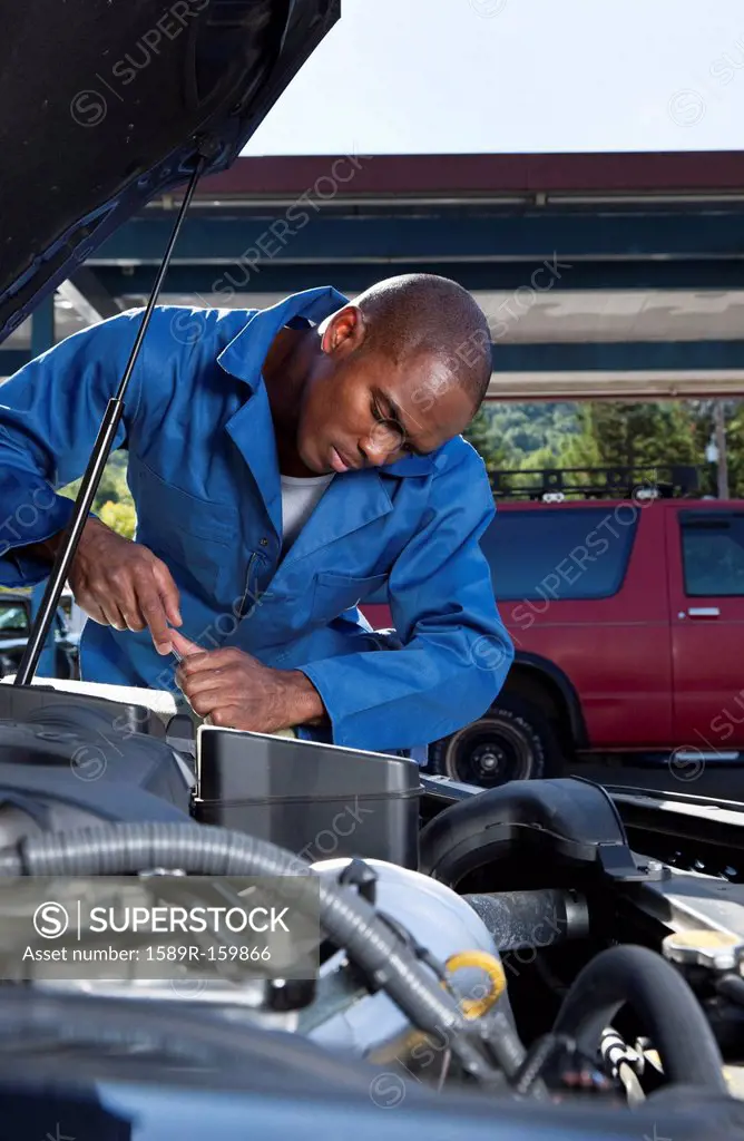 Black mechanic working on car engine