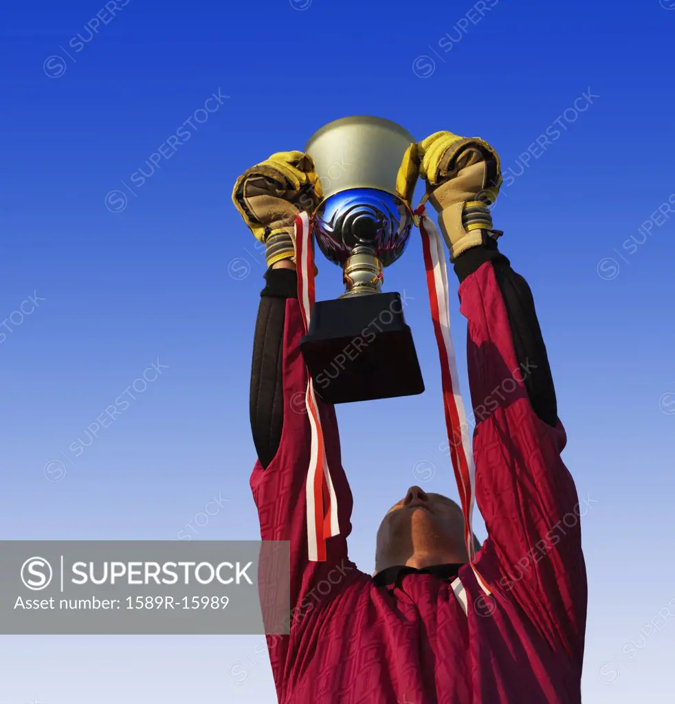 Male goalie triumphantly holding up trophy