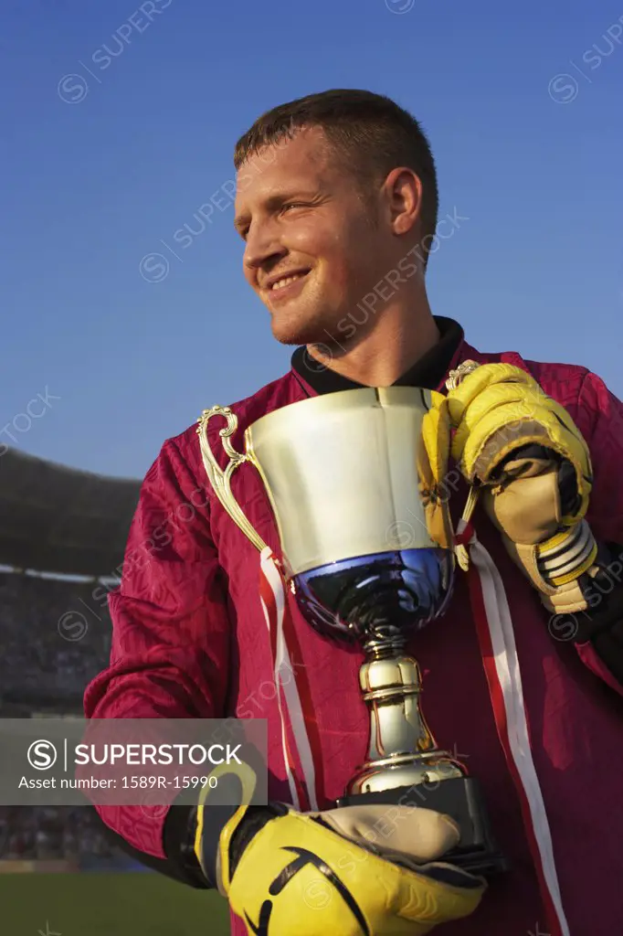 Male goalie triumphantly holding trophy