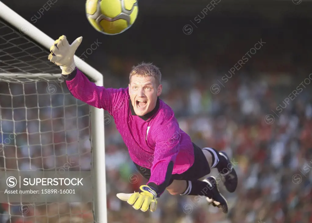 Male goalie reaching for the ball in midair