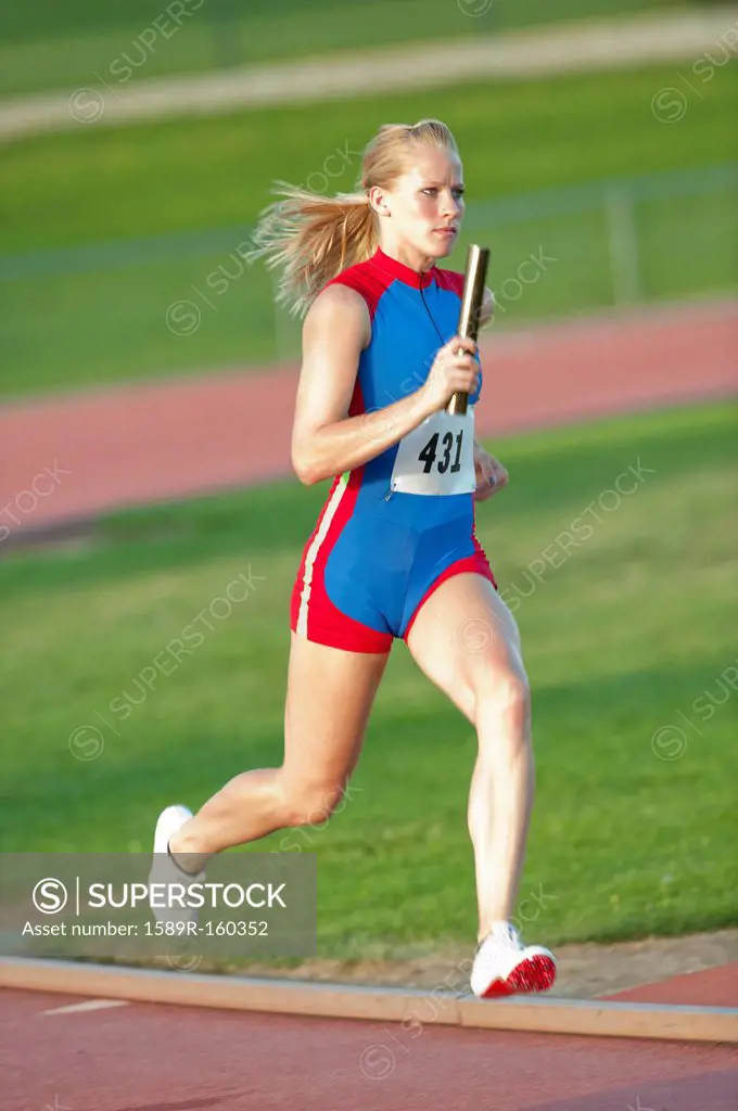 Caucasian runner holding baton running on track