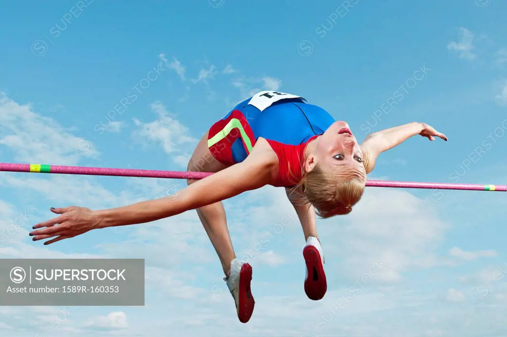 Caucasian athlete jumping over bar