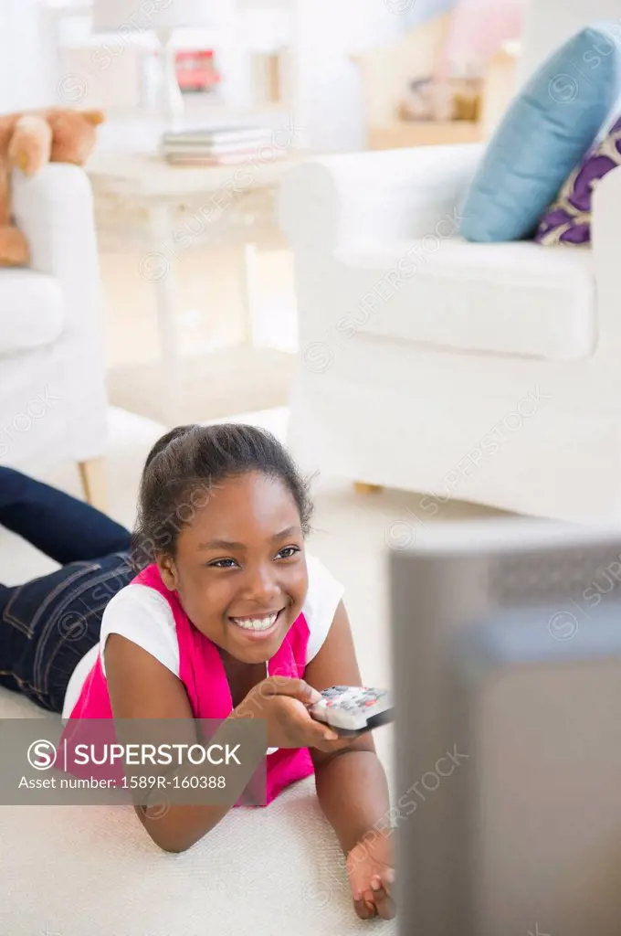 Black girl laying on floor watching television