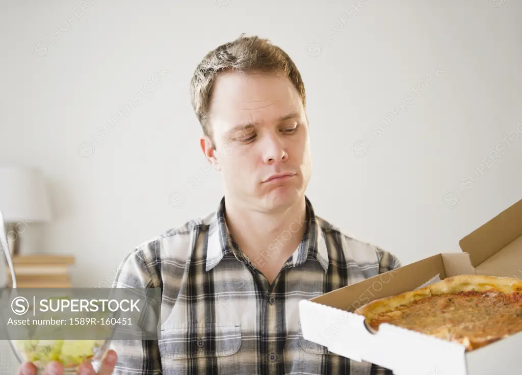 Caucasian man looking at pizza in box