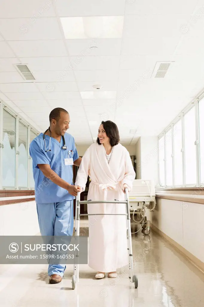 Nurse helping patient use walker in hospital