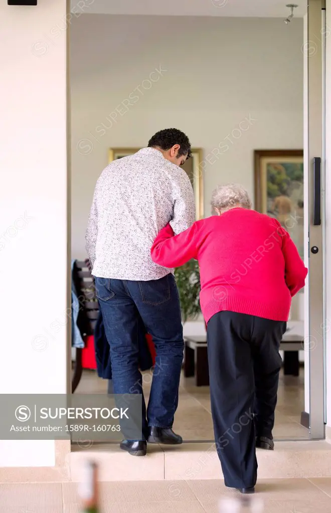 Hispanic man helping his grandmother to walk
