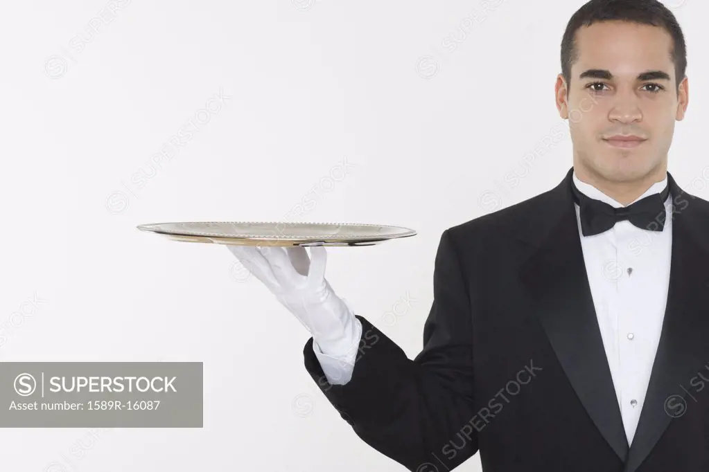 Portrait of male waiter balancing tray