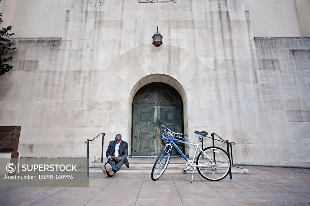 Businessman sitting on steps near bicycle