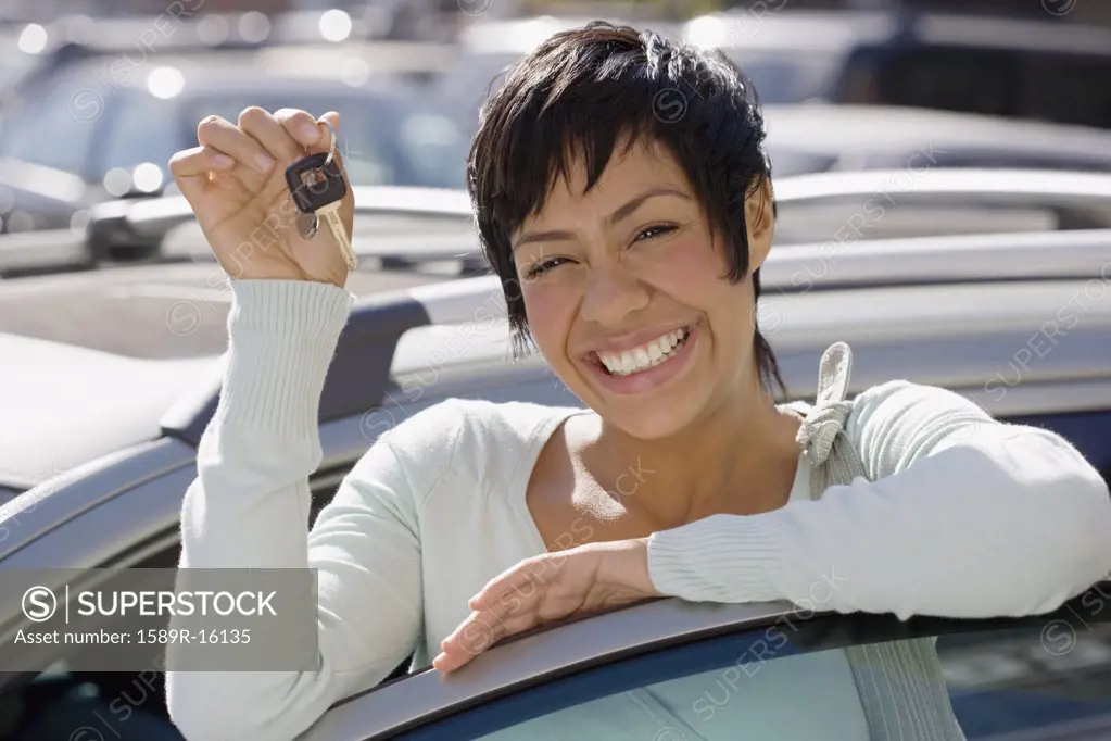 Portrait of woman holding car keys and standing with car door open