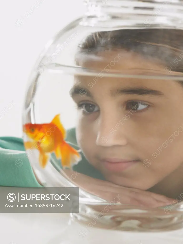 Young girl watching a goldfish in a fishbowl