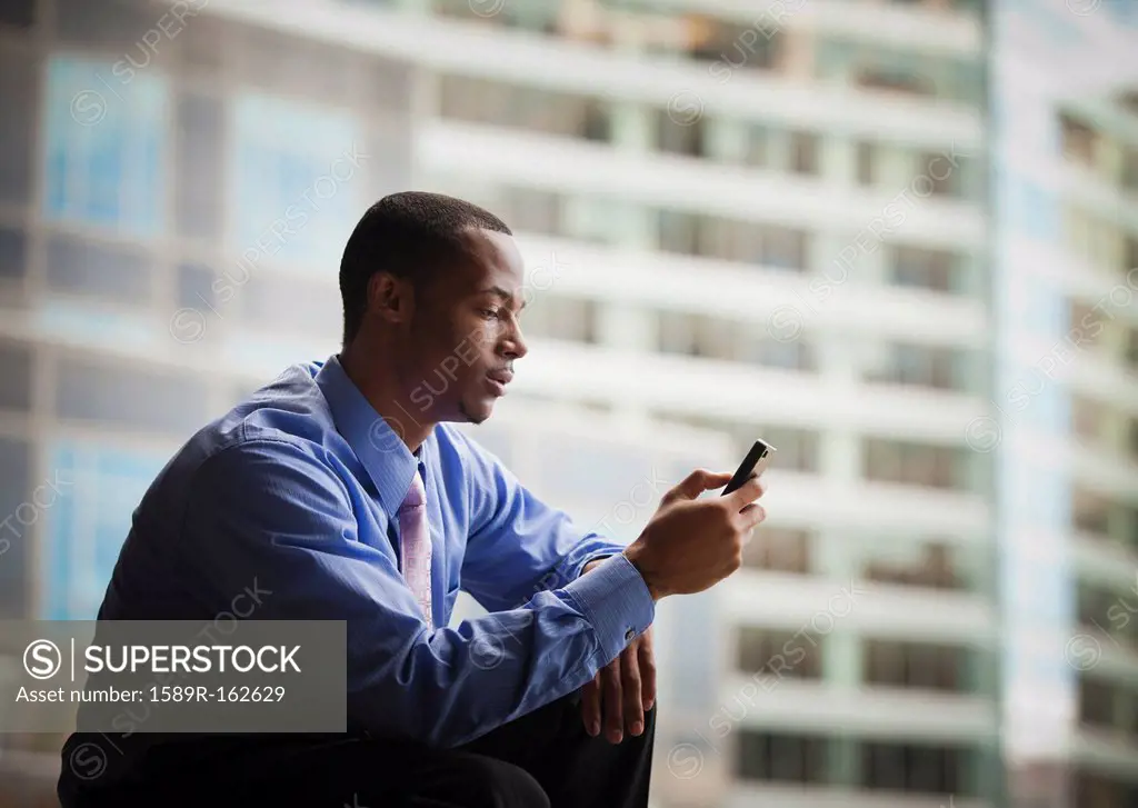Black businessman text messaging on cell phone