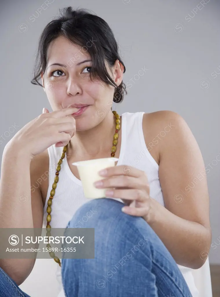 Young woman eating pudding with her fingers