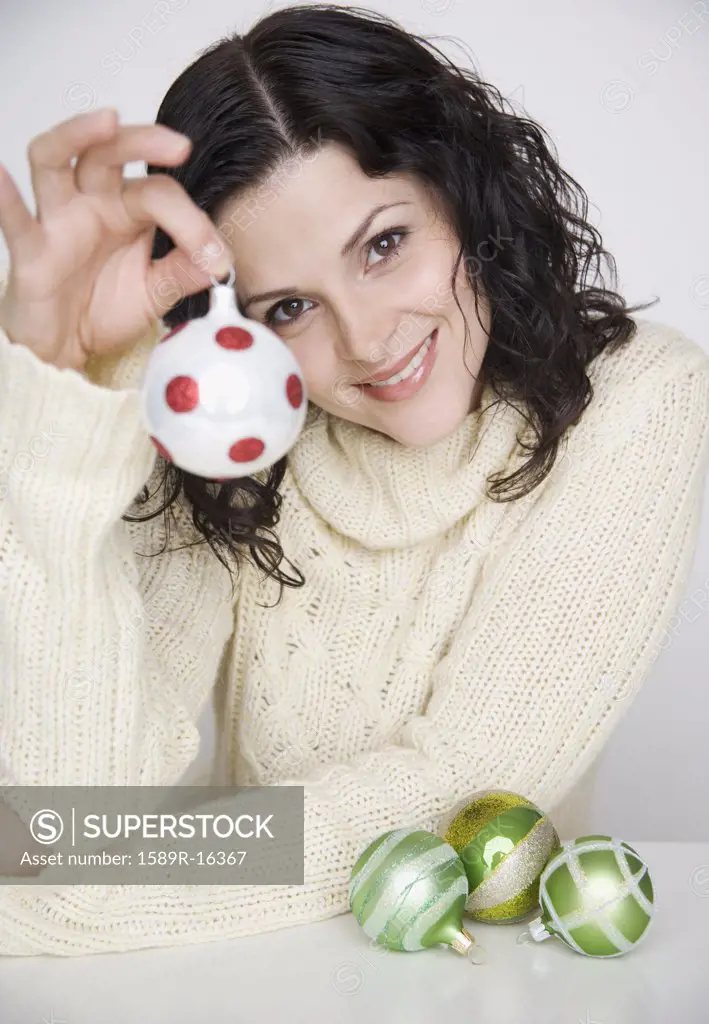 Portrait of woman holding up Christmas ornament