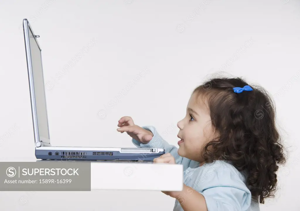 Young girl playing with laptop computer