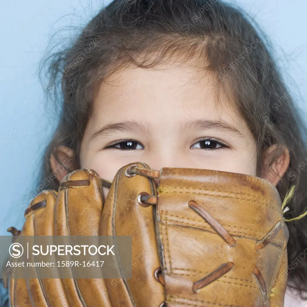Portrait of girl with baseball mitt covering mouth