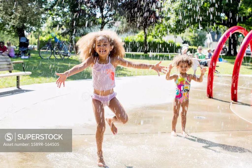 Mixed race girls playing in fountain