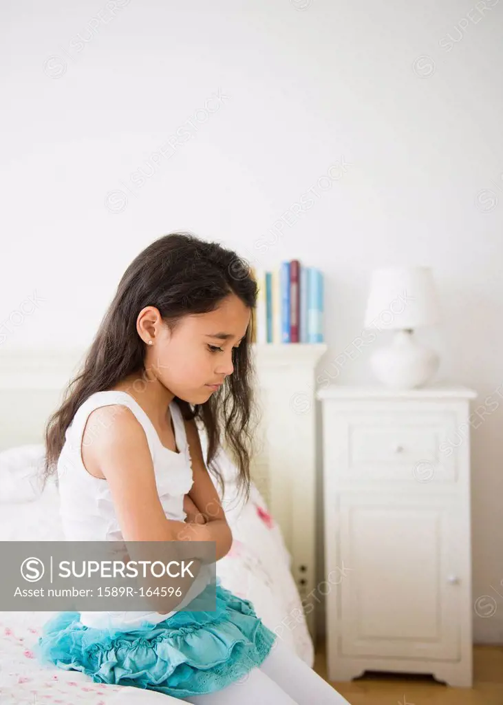 Mixed race girl sitting on bed