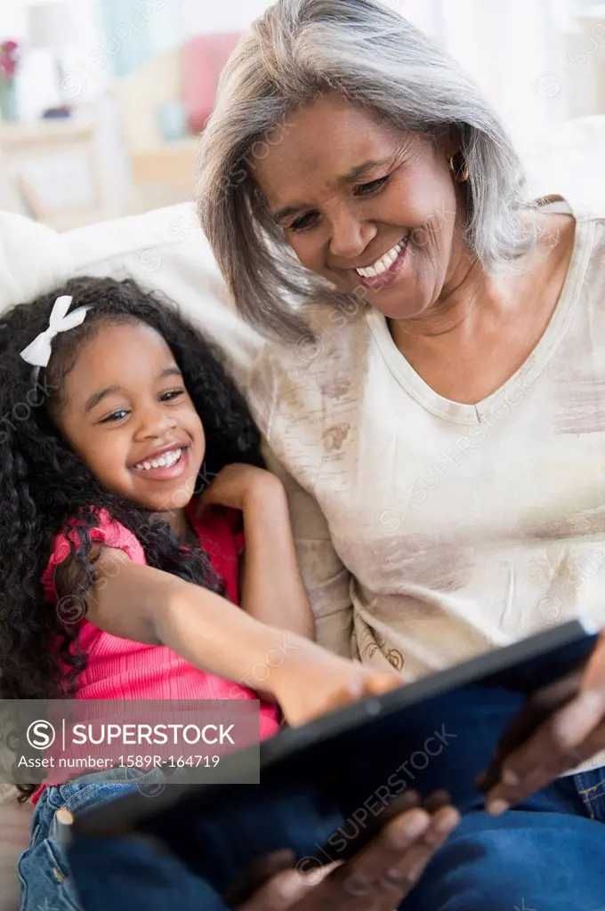 African American grandmother and granddaughter looking at digital tablet
