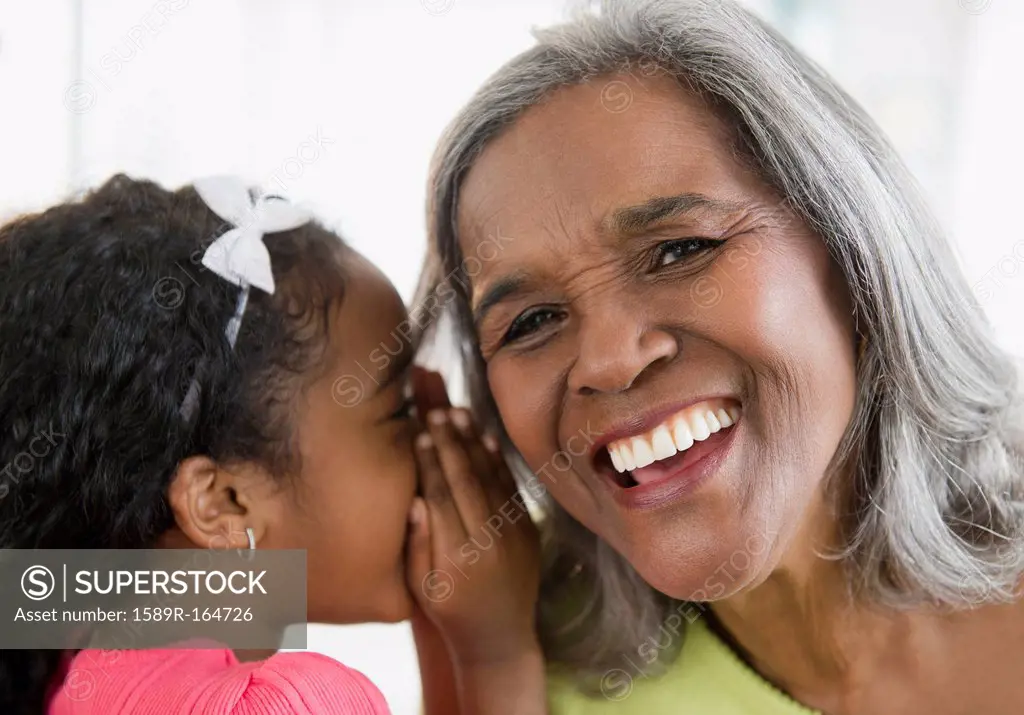 African American girl telling secret to grandmother