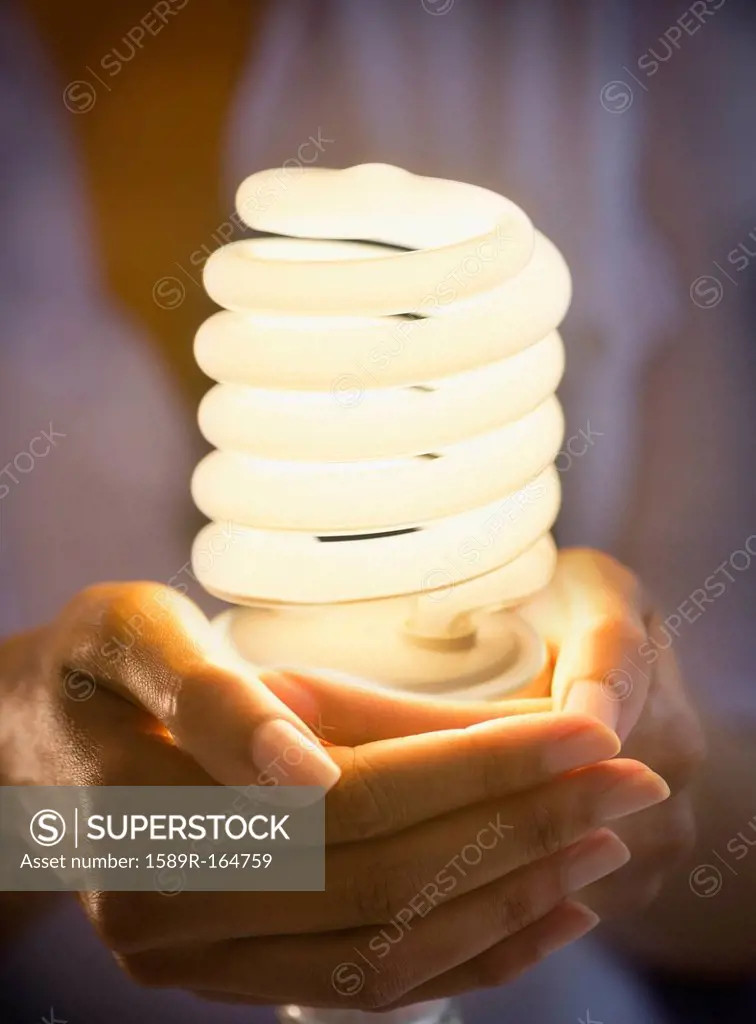 Cape Verdean woman holding CFL light bulb