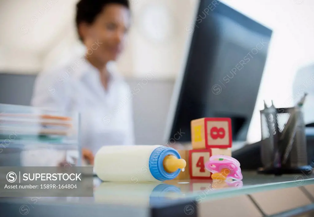 Baby bottle and blocks on African American woman´s desk