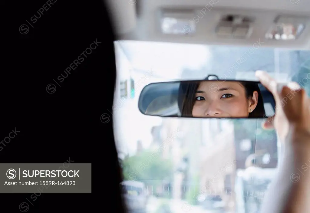 Asian woman adjusting rear_view mirror
