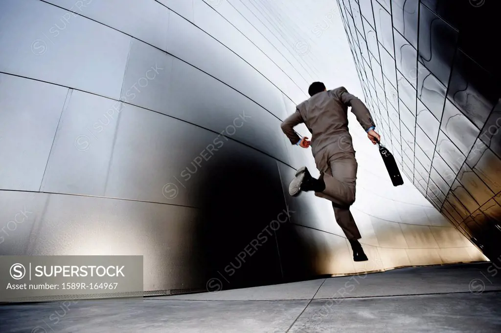 Businessman running down urban alley