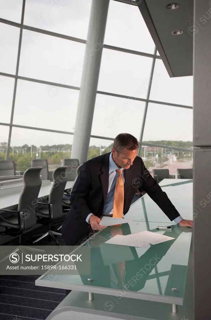 Caucasian businessman looking at paperwork in conference room