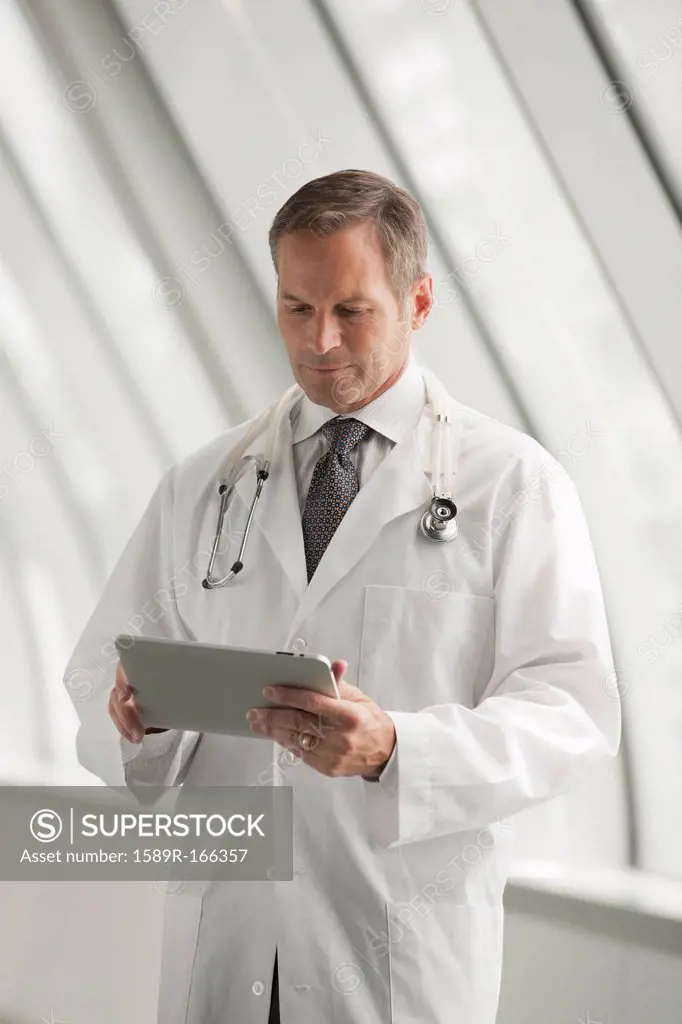 Caucasian doctor using digital tablet in hospital corridor
