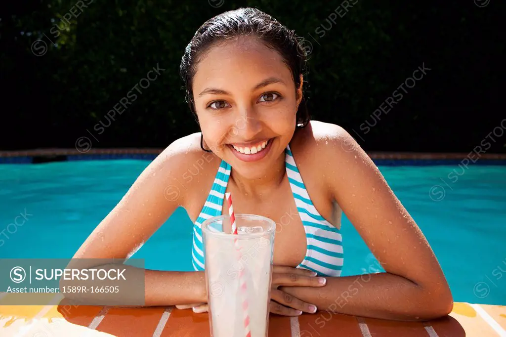 Mixed race girl drinking lemonade near swimming pool